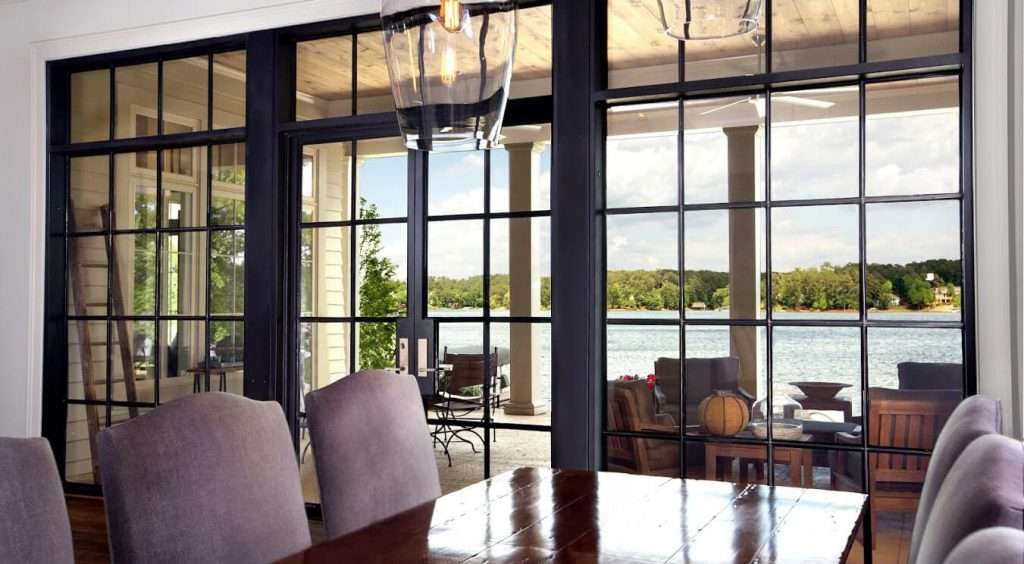 large kitchen table with grey chair beside steel glass doors looking out to patio pool and mountains