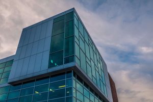 industrial office building with all glass windows in front of cloudy skies