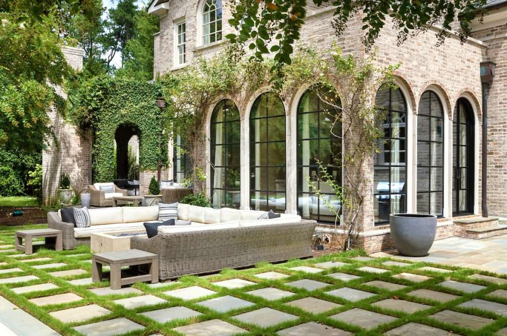 exterior of brick home with overgrown plants on black steel windows and doors